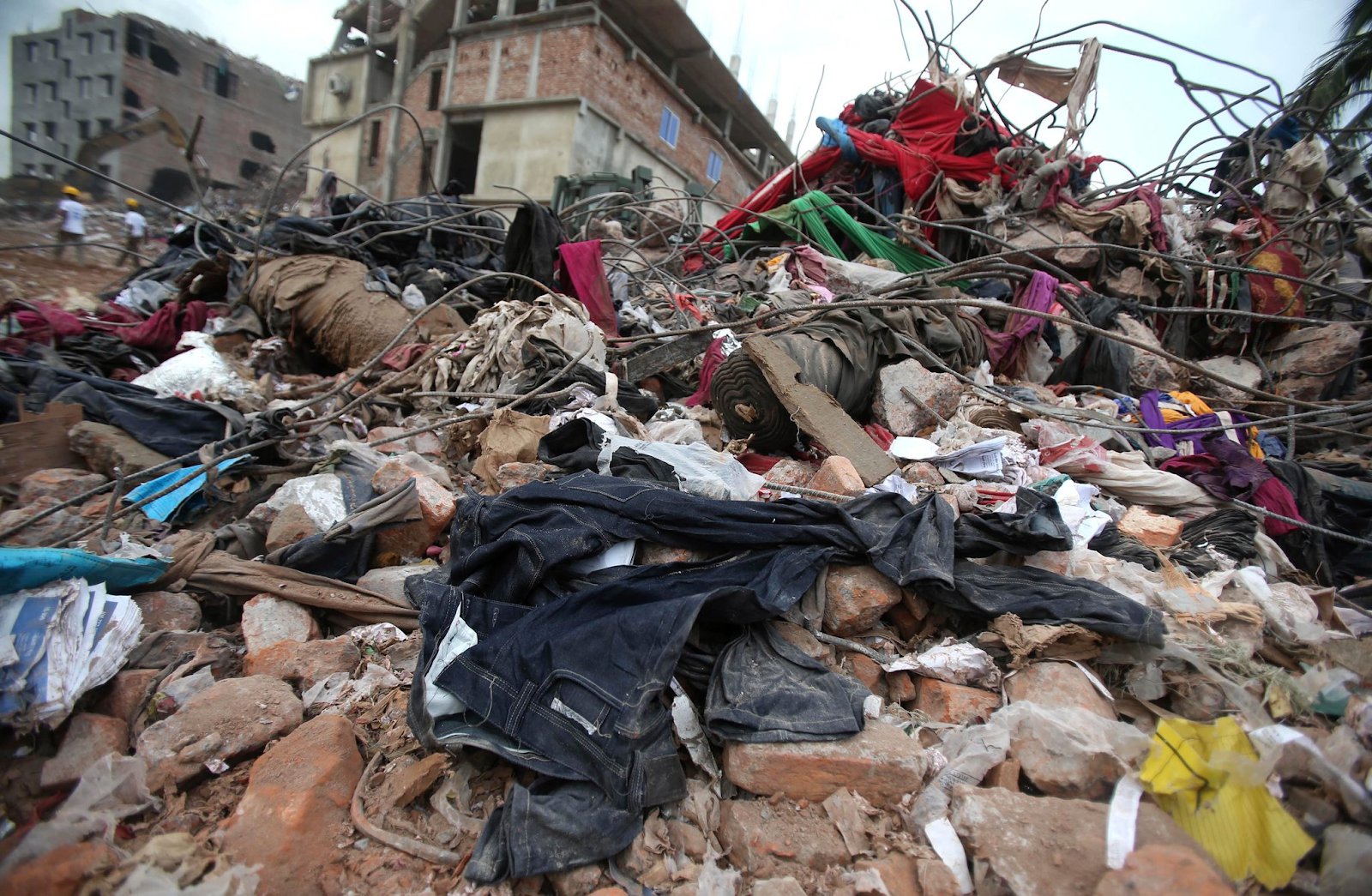 Fast fashion items discarded among other garbage, rubble, and debris