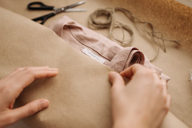 Image of a person wrapping a clothing item in brown craft paper